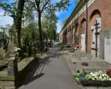 Aleja przez zabytkową nekropolię z nagrobkami i mauzoleami wzdłuż ceglanego muru z arkadami.