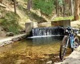 Bicicleta de montaña junto a una cascada en un arroyo, ideal para rutas por Segovia.