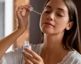 Una mujer aplica serum en su rostro con un gotero. Descubre qué es serum y cómo puede mejorar tu piel.