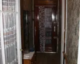 Couloir d'une maison bordeaux typique, avec une porte en bois, un porte-manteau et un papier peint fleuri.