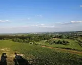 Widok z góry Siewierskiej na zielone pola i lasy, w oddali widać zabudowania i kominy.