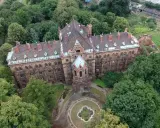 Mokrzeszów pałac, rozległy, ceglany budynek z charakterystycznym dachem, otoczony bujną zielenią.