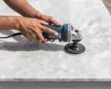 Manos puliendo una encimera de mármol con una lijadora. El proceso de como pulir mármol para dejarlo brillante.