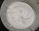 Crème fouettée onctueuse dans un bol en métal, prête à garnir un délicieux gâteau.