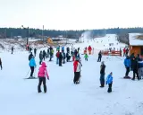 Ludzie jeżdżą na nartach i snowboardach, ciesząc się zimowymi atrakcjami. Warunki na stokach wydają się dobre, śnieg jest obecny, a pogoda sprzyja aktywnościom na świeżym powietrzu.