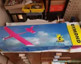 DYMOND RC-Flugzeug-Karton mit pinkem Modell. Ein gelber Streifen mit dem Schriftzug DYMOND.