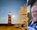 Rött och vitt fyr på Gotland i månsken, bredvid ett träd med gyllene löv. Till höger en glad man med glasögon.