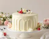 Gâteau élégant avec un glaçage sans chocolat blanc, décoré de fruits rouges, de baies et de fleurs fraîches.