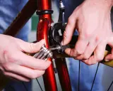 Dłoń dokręca śrubę klocka hamulcowego przy rowerze. Zastanawiasz się, jakie klocki hamulcowe do roweru tarczowe wybrać?