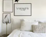 Un lit douillet avec une tête de lit DIY, des coussins texturés et des cadres muraux inspirants.