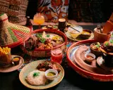 En härlig måltid på en afrikansk restaurang med flera rätter, drycker och en färgglad duk.