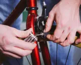 Dłonie dokonują wymiany hamulców w rowerze, używając klucza imbusowego do regulacji.