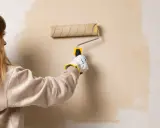 Persona aplicando pintura con rodillo, un truco para pintar sin cinta de carrocero y lograr bordes perfectos.