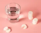 Ein Glas Wasser und Magnesium-Brausetabletten auf rosa Untergrund. Hilft Magnesium beim Einschlafen?