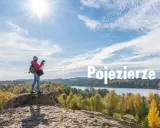 Idealne miejsce na weekend: dziewczyna z aparatem na wydmie podziwia jesienne krajobrazy nad Jeziorem Ełckim.