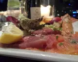 Un piatto di pesce crudo, con salmone, tonno e scampi, accompagnato da limone e insalata. Un'ottima occasione per degustazioni gastronomiche.
