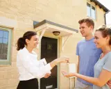 Une agent immobilier remet les clés d'une maison à un jeune couple. Ils sont heureux d'acquérir leur nouveau logement, peut-être grâce au droit de préemption locataire.