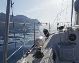 Vue depuis un voilier Aquila, naviguant sur une mer calme avec des falaises en arrière-plan. Avis de navigation paisible.