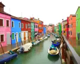 Venise : une maison colorée et d'autres maisons aux teintes vives bordent un canal où flottent des bateaux.