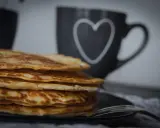Stapel goldbrauner, **high protein pancakes** auf schwarzem Teller, daneben eine Tasse mit Herz.