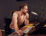 Un ingé son concentré devant son micro, prêt à enregistrer.