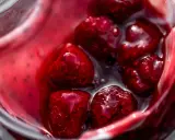 Gros plan sur des framboises dans un liquide rouge vif, parfait pour un nappage framboise facile et gourmand.