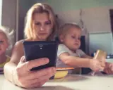Madre con su móvil, mientras sus hijos pequeños, de unos 2 años, miran pantallas.