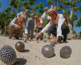 Des hommes jouent à la pétanque sous les platanes. La question "la pétanque est-il un sport ?" se pose devant leur concentration.