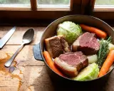 Un plat mijoté de potee au chou, avec des morceaux de bœuf, des carottes, du chou et des herbes, prêt à être cuit.