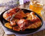Muslos de pollo al horno dorados, servidos con rodajas de limón y un tarro de miel.