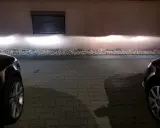 Jasne światła z przodu Audi A4 B6 oświetlają ścianę.