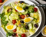 Frischer Salat mit knackigem Eisbergsalat, Tomaten, Gurken, Oliven, Mais und Eiern. Ein herzhafter Thunfischsalat, der Lust auf mehr macht.