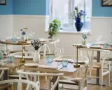 Vackert dukade bord med blåa glas och blommor i vaser, redo för gäster på en av restaurangerna i Skagen.