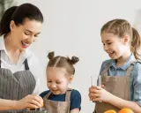 Mama z córkami robi sok pomarańczowy. To pyszne źródło witaminy A dla dzieci, które wspiera ich rozwój i odporność.