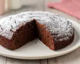 Una deliziosa torta al cioccolato, spolverata di zucchero a velo, con una fetta mancante, pronta per essere gustata.