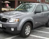 Szary Mazda Tribute zaparkowany na parkingu przed sklepem.