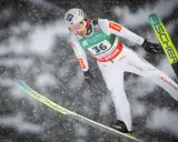Skoczek narciarski w locie, przygotowuje się do lądowania. Widoczny numer 36. To może być zapowiedź skoki narciarskie 2026.