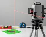Poziomica laserowa z czerwonymi liniami, miarką, tarczą celowniczą i poziomicą libellową.