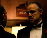 Marlon Brando nei panni di Don Corleone, un'icona de "Il Padrino", in una scena che riassume la sua recensione: potere e dramma.