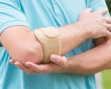 Mann mit Bandage am Ellenbogen, um Schmerzen bei Tennisarm zu lindern.
