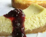 Pyszny sernik z serka wiejskiego polany wiśniową konfiturą, kusi swoim kremowym wnętrzem i chrupiącym spodem.