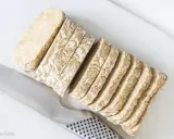 Pokrojony w plastry tempeh, czyli fermentowana soja, leży obok noża. To świetny składnik do wegańskich potraw.