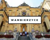 Bazylika w Wambierzycach, znana z licznych atrakcji, zachwyca architekturą. Widać schody prowadzące do sanktuarium, ozdobione czerwonymi kwiatami.