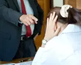 Szef wskazuje palcem na pracownika, który ukrywa twarz w dłoniach. Widać tu negatywne cechy pracownika, takie jak brak pewności siebie i stres.