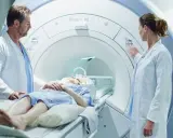 Pacjentka leży w aparacie do rezonansu magnetycznego, a lekarze przygotowują badanie z kontrastem.