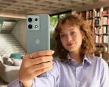 Kobieta robi selfie telefonem Motorola E6 Play w nowoczesnym wnętrzu.