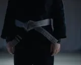 Dziecko w czarnym judogi z szarym pasem, symbolizującym drogę do mistrzostwa.