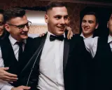 Uśmiechnięci panowie w garniturach, przygotowujący się na ekstremalny wieczór kawalerski.