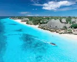Idealna pogoda na Zanzibarze w czerwcu: turkusowa woda, biała plaża i łódź z turystami.