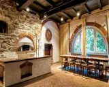 Tavernetta moderna piccola con forno a legna in pietra, bancone in muratura e un lungo tavolo in legno con sedie.